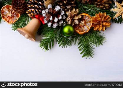 Christmas greeting with jingle bell, dried oranges and green ornament . Christmas background with handmade decorations. Christmas decoration with fir branches and pine cones. Copy space