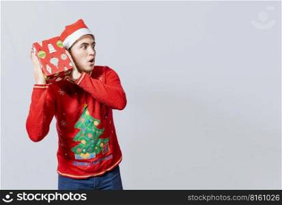 Christmas guy holding and listening a gift box. Excited christmas people holding and listening a gift. Concept of guessing a christmas gift, Christmas man holding and listening a gift box