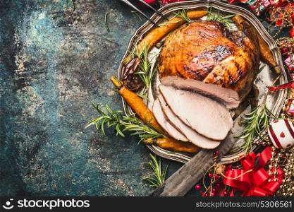 Christmas ham served with roasted vegetables and festive decorations on vintage background, top view, place for text. Christmas recipes and dishes concept