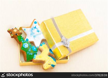 Christmas handmade gingerbread cakes with icing and decoration sweet dessert in golden gift box with silver ribbon on paper background. Holiday concept.