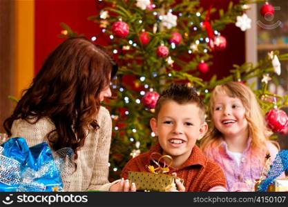 Christmas - happy family (mother with son and daughter) with gifts on Xmas Eve