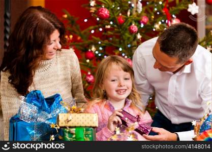 Christmas - happy family (parents with daughter) with gifts on Xmas Eve