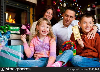 Christmas - happy family (parents with son and daughter) with gifts on Xmas Eve