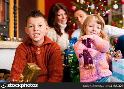 Christmas - happy family (parents with son and daughter) with gifts on Xmas Eve