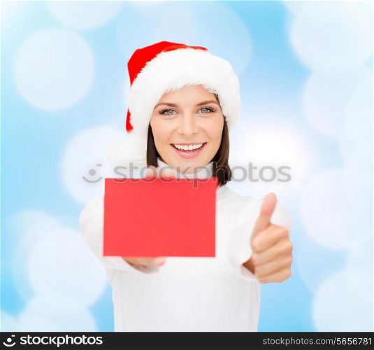 christmas, holdays, people, advertisement and sale concept - happy woman in santa helper hat with blank red card showing thumbs up gesture over blue lights background
