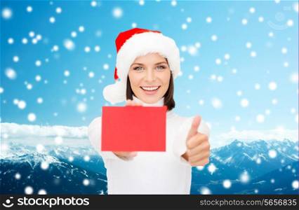 christmas, holdays, people, advertisement and sale concept - happy woman in santa helper hat with blank red card showing thumbs up gesture over snowy mountains background