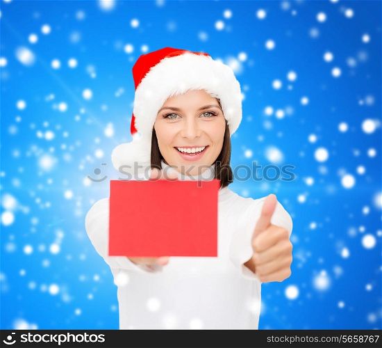 christmas, holdays, people, advertisement and sale concept - happy woman in santa helper hat with blank red card showing thumbs up gesture over blue snowy background