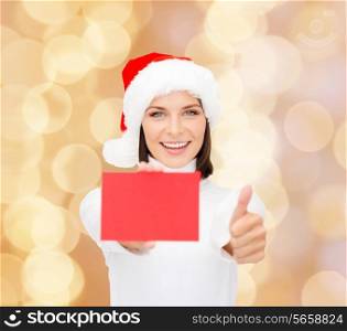 christmas, holdays, people, advertisement and sale concept - happy woman in santa helper hat with blank red card showing thumbs up gesture over beige lights background