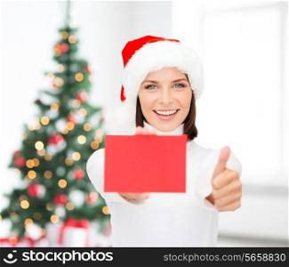 christmas, holdays, people, advertisement and sale concept - happy woman in santa helper hat with blank red card showing thumbs up gesture over living room and christmas tree background