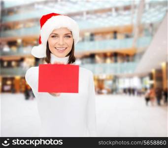 christmas, holdays, people, advertisement and sale concept - happy woman in santa helper hat with blank red card over shopping center background