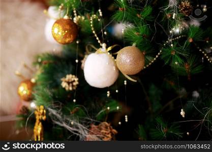 Christmas holiday background. Golden and white bauble hanging from a decorated on tree with bokeh and snow, copy space. Christmas holiday background. Golden and white bauble hanging from a decorated on tree with bokeh and snow, copy space.