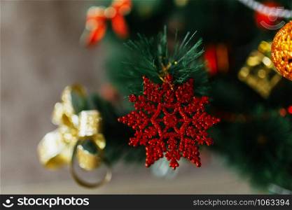 Christmas holiday background. Red star hanging from a decorated on christmas tree with golden bows and balls. Selective focus. Close up. Christmas holiday background. Red star hanging from a decorated on christmas tree with golden bows and balls. Selective focus. Close up.