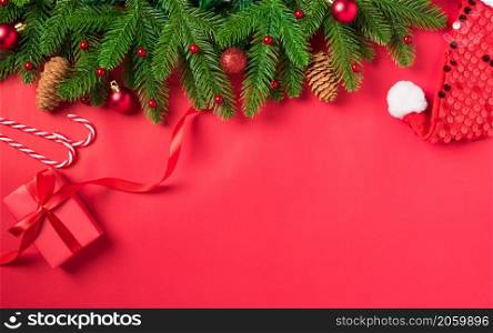 Christmas holiday background with gift box decorations composition, Top view fir green fir tree branches and Xmas ornaments gift box on a red table background, Happy New Year Day concept