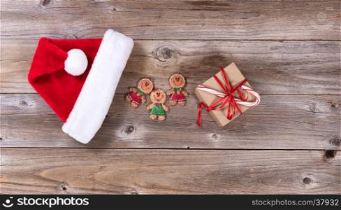 Christmas holiday cookies, gift and Santa cap on rustic wood.