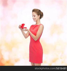 christmas, holiday, valentine&#39;s day and celebration concept - smiling young woman in red dress with gift box