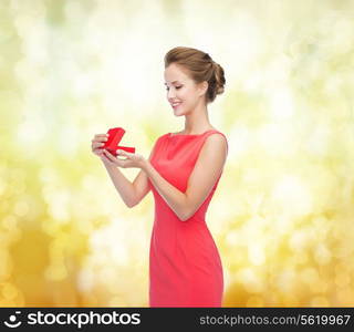 christmas, holiday, valentine&#39;s day and celebration concept - smiling young woman in red dress with gift box