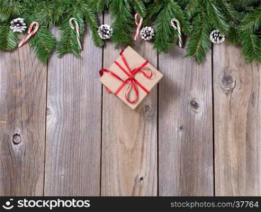 Christmas holiday wooden background with fir branches and gift box forming upper border