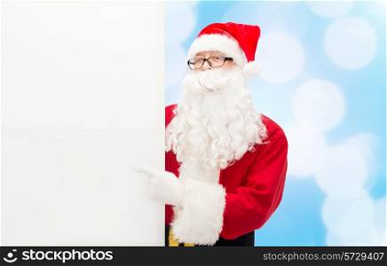 christmas, holidays, advertisement and people concept - man in costume of santa claus with white blank billboard over blue lights background