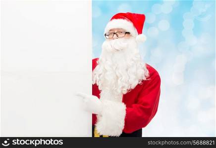 christmas, holidays, advertisement, gesture and people concept - man in costume of santa claus pointing finger to white blank billboard over blue lights background