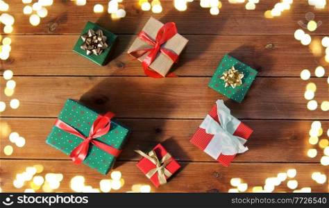 christmas, holidays and celebration concept - gift boxes on wooden boards from top over festive lights. christmas gifts on wooden boards over lights