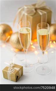 christmas, holidays and celebration concept - two glasses of champagne, gifts and decorations. glasses of champagne and christmas gifts
