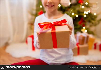 christmas, holidays and childhood concept - close up of girl in pajama with gift box at home. close up of girl with christmas gift at home