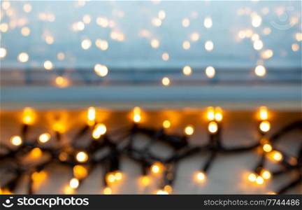 christmas, holidays and illumination concept - blurred electric garland lights on window sill. blurred electric garland lights on window sill