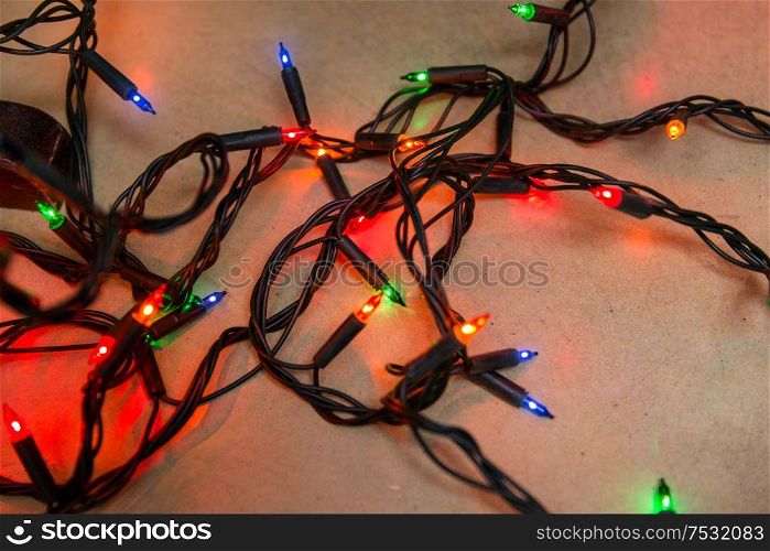 christmas, holidays and illumination concept - electric garland lights on wooden background. christmas garland lights on wooden background