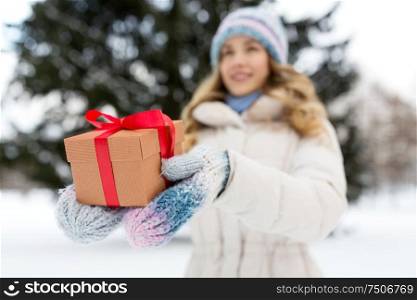 christmas, holidays and leisure concept - close up of happy young woman with gift box outdoors in winter. close up of woman with christmas gift in winter