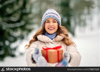 christmas, holidays and leisure concept - happy young woman with gift box outdoors in winter. happy young woman with christmas gift in winter
