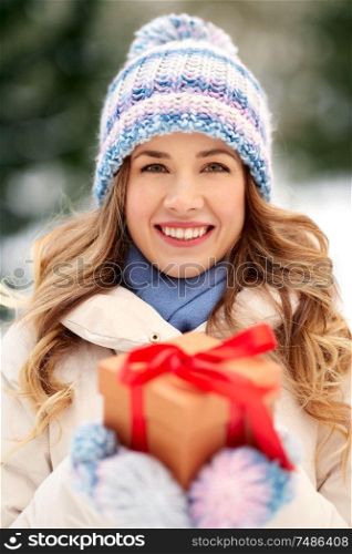 christmas, holidays and leisure concept - happy young woman with gift box outdoors in winter. happy young woman with christmas gift in winter
