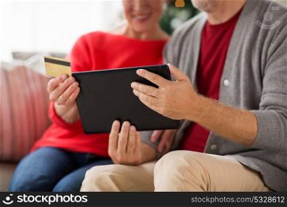 christmas, holidays and people concept - close up of happy smiling senior couple with tablet pc computer and credit card shopping online at home. senior couple with tablet pc shopping online