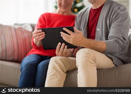 christmas, holidays and people concept - close up of happy smiling senior couple with tablet pc computer at home. senior couple with tablet pc at christmas
