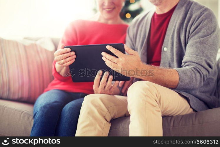 christmas, holidays and people concept - close up of happy smiling senior couple with tablet pc computer at home. senior couple with tablet pc at christmas