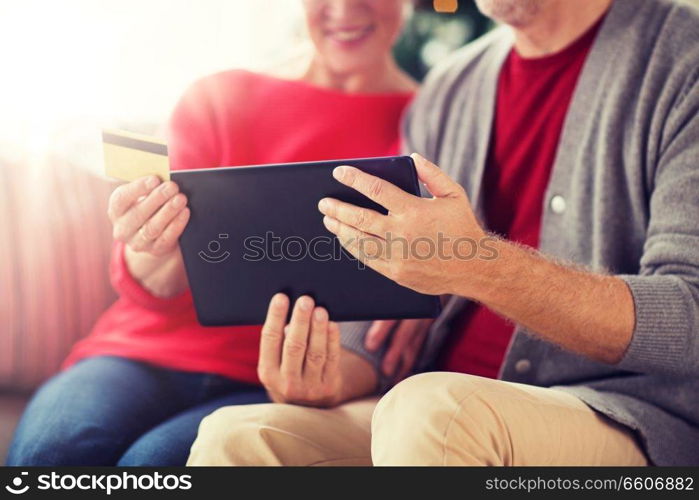 christmas, holidays and people concept - close up of happy smiling senior couple with tablet pc computer and credit card shopping online at home. senior couple with tablet pc shopping online