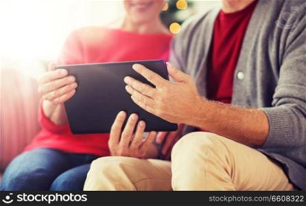christmas, holidays and people concept - close up of happy smiling senior couple with tablet pc computer at home. senior couple with tablet pc at christmas