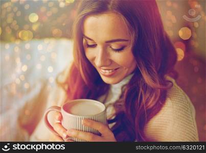 christmas, holidays and people concept - close up of happy young woman with cup of coffee or cocoa drink at home. close up of woman drinking cocoa at christmas