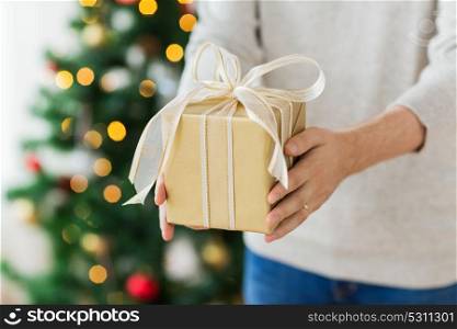 christmas, holidays and people concept - close up of man with gift box at home. close up of man with christmas gift at home
