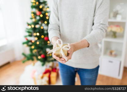 christmas, holidays and people concept - close up of man with gift box at home. close up of man with christmas gift at home