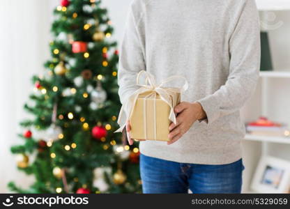 christmas, holidays and people concept - close up of man with gift box at home. close up of man with christmas gift at home