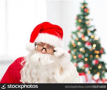 christmas, holidays and people concept - close up of santa claus in glasses winking over living room with tree
