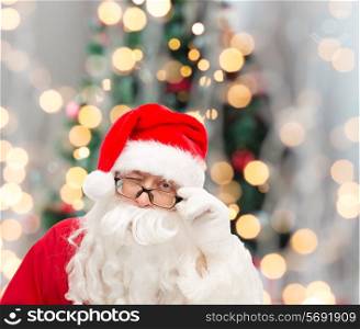 christmas, holidays and people concept - close up of santa claus in glasses winking over tree lights background