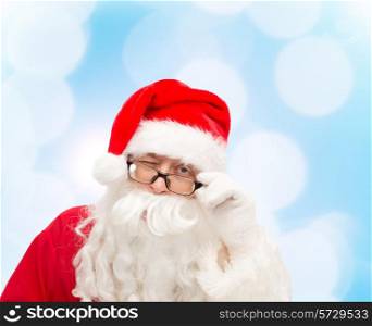 christmas, holidays and people concept - close up of santa claus in glasses winking over blue lights background
