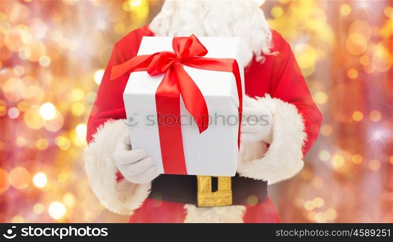 christmas, holidays and people concept - close up of santa claus with gift box over lights background