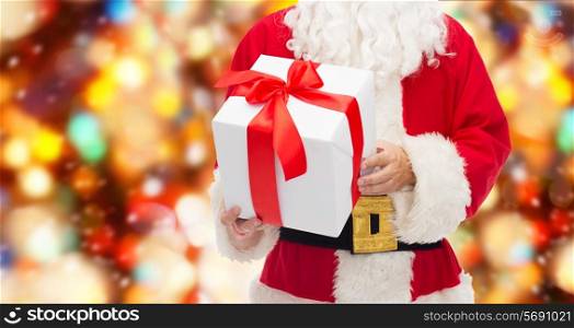 christmas, holidays and people concept - close up of santa claus with gift box over red lights background
