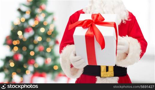 christmas, holidays and people concept - close up of santa claus with gift box over living room with tree