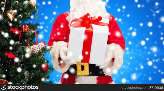 christmas, holidays and people concept - close up of santa claus with gift box and tree over blue snowy background