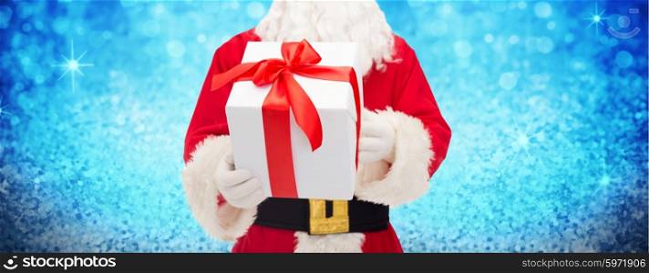 christmas, holidays and people concept - close up of santa claus with gift box over lights or blue glitter background