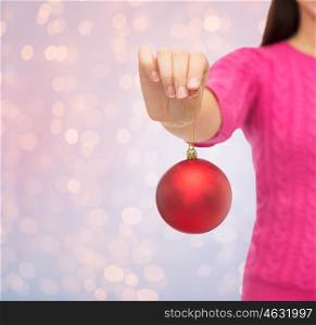 christmas, holidays and people concept - close up of smiling woman in pink sweater holding christmas ball over rose quartz and serenity lights background