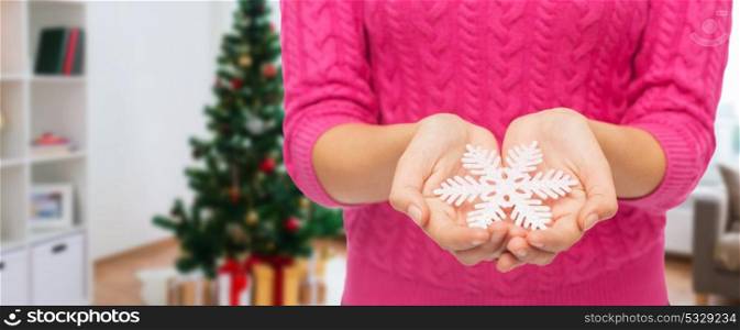 christmas, holidays and people concept - close up of woman in pink sweater holding snowflake. close up of woman hands with christmas snowflake